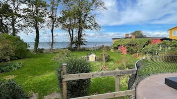 Un jardín con una valla de madera, un cobertizo pequeño y vista al mar.
