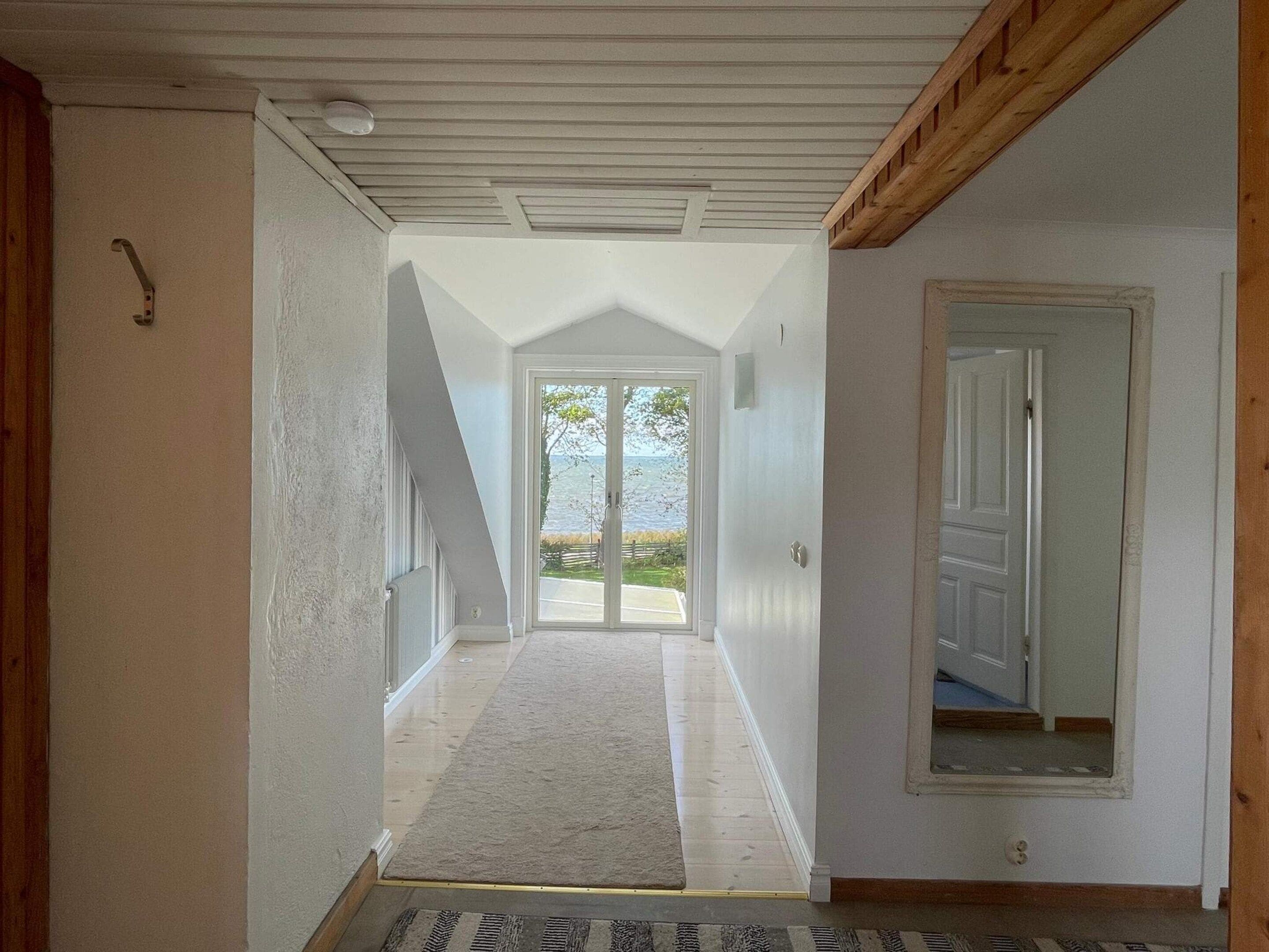A hallway with a view to the outside, a door on the right, and a small window on the left.