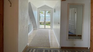 Un couloir donnant sur l’extérieur, une porte à droite et une petite fenêtre à gauche.