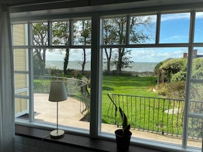 A room with large windows offering a view of a well-maintained garden and a body of water. - Holiday Home in Mörbylånga (Morbylanga)