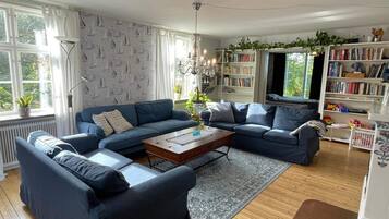 A living room with a blue sofa set, a wooden coffee table, and a bookshelf filled with books.