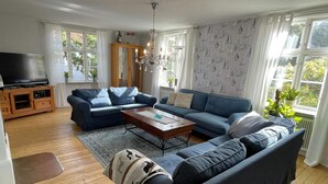 Un salon moderne avec un canapé d’angle, une table basse en bois et un téléviseur posé sur un meuble.