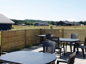 An outdoor patio area with tables and chairs, a wooden fence, and houses in the background.