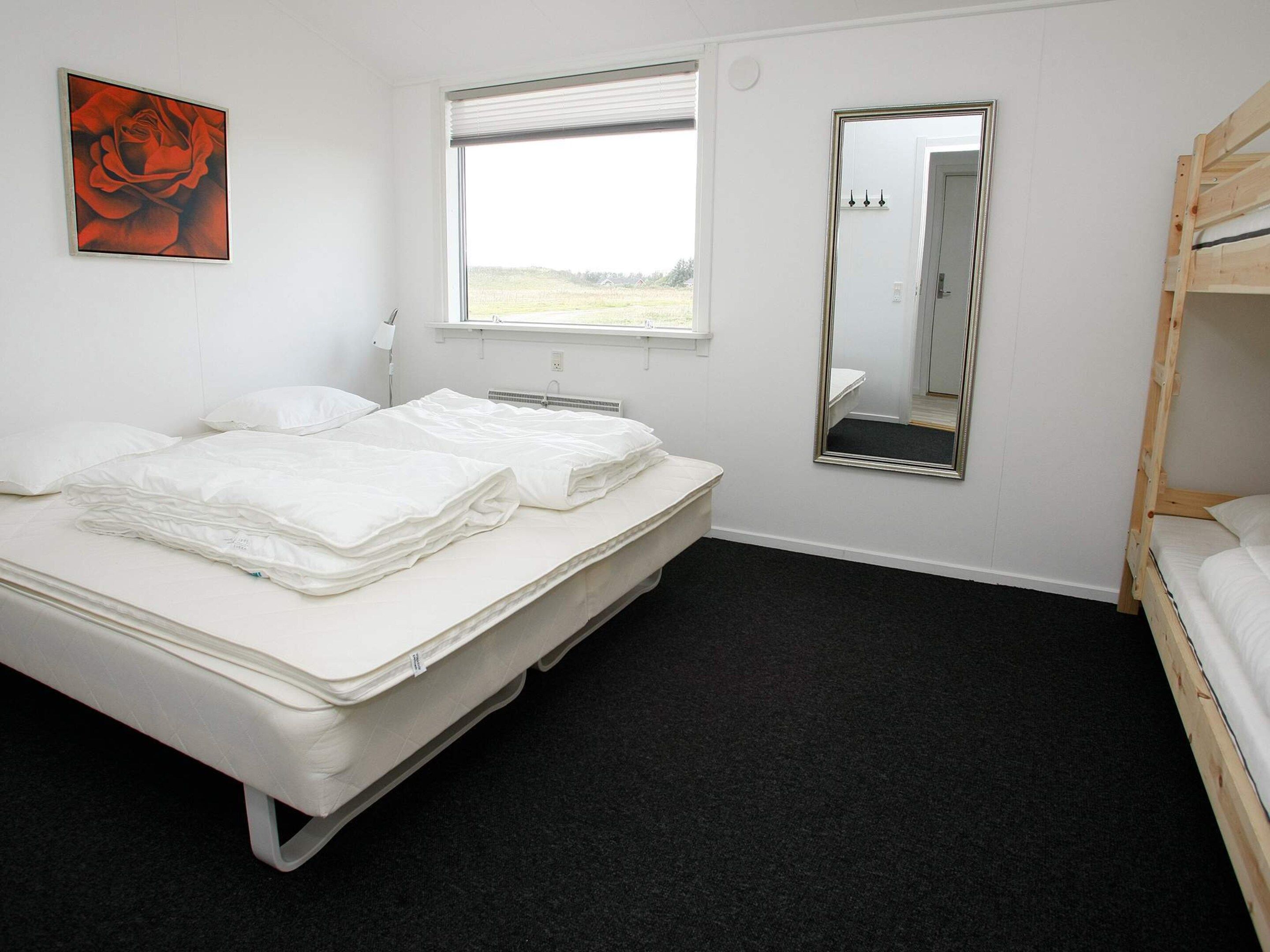 Ein Hotelzimmer mit einem Bett, einem Fenster, einem Spiegel und einem Bild an der Wand.