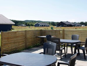 An outdoor patio area with tables and chairs, a wooden fence, and houses in the background.