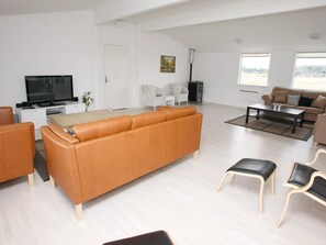A modern living room with a leather sofa, a television, and a fireplace.