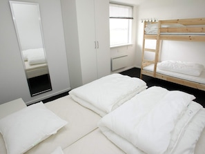 Quarto com beliche, guarda-roupa, espelho e janela com persianas.