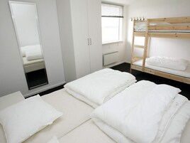 A bedroom with a bunk bed, a wardrobe, a mirror, and a window with blinds.