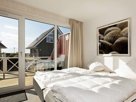 Un dormitorio con cama, ventana grande y vista a un edificio.