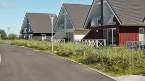 A row of modern, triangular-roofed buildings with large windows, a paved road in front, and a clear sky. - Holiday Home in Wendtorf (Wendtorf)