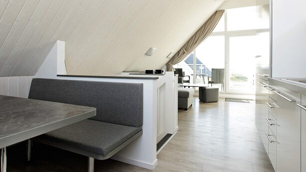 A modern loft-style room with a dining area, kitchenette, and a large window providing natural light. - Holiday Home in Wendtorf (Wendtorf)