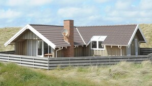 A coastal house with a sloped roof, a chimney, and a small deck. - 4 Star Holiday Home in Ringkobing (Ringkobing)