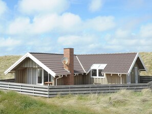 A coastal house with a sloped roof, a chimney, and a small deck. - 4 Star Holiday Home in Ringkobing (Ringkobing)