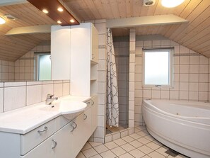 A bathroom with a large bathtub, a shower, and a sink with cabinets.