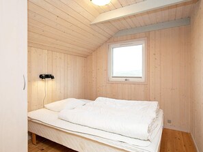 A single bed in a room with wooden walls and a sloped ceiling. - 4 Star Holiday Home in Ringkobing (Ringkobing)