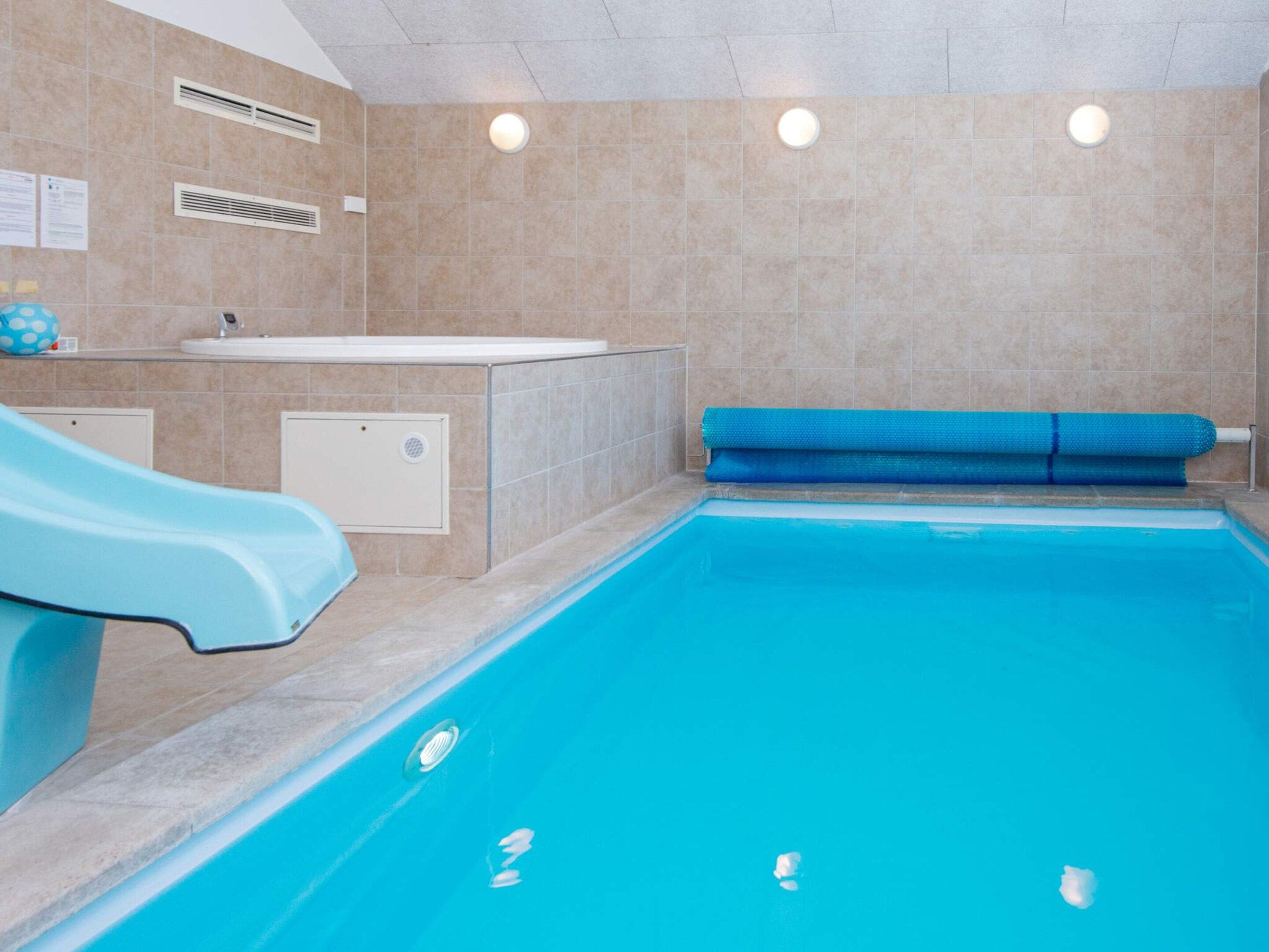 En pool med en vattenrutschkana, ett bubbelbad och en blå matta.