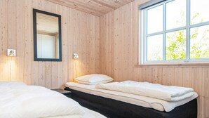 Una habitación con dos camas, un ventanal con vista a la vegetación y un espejo montado en la pared.