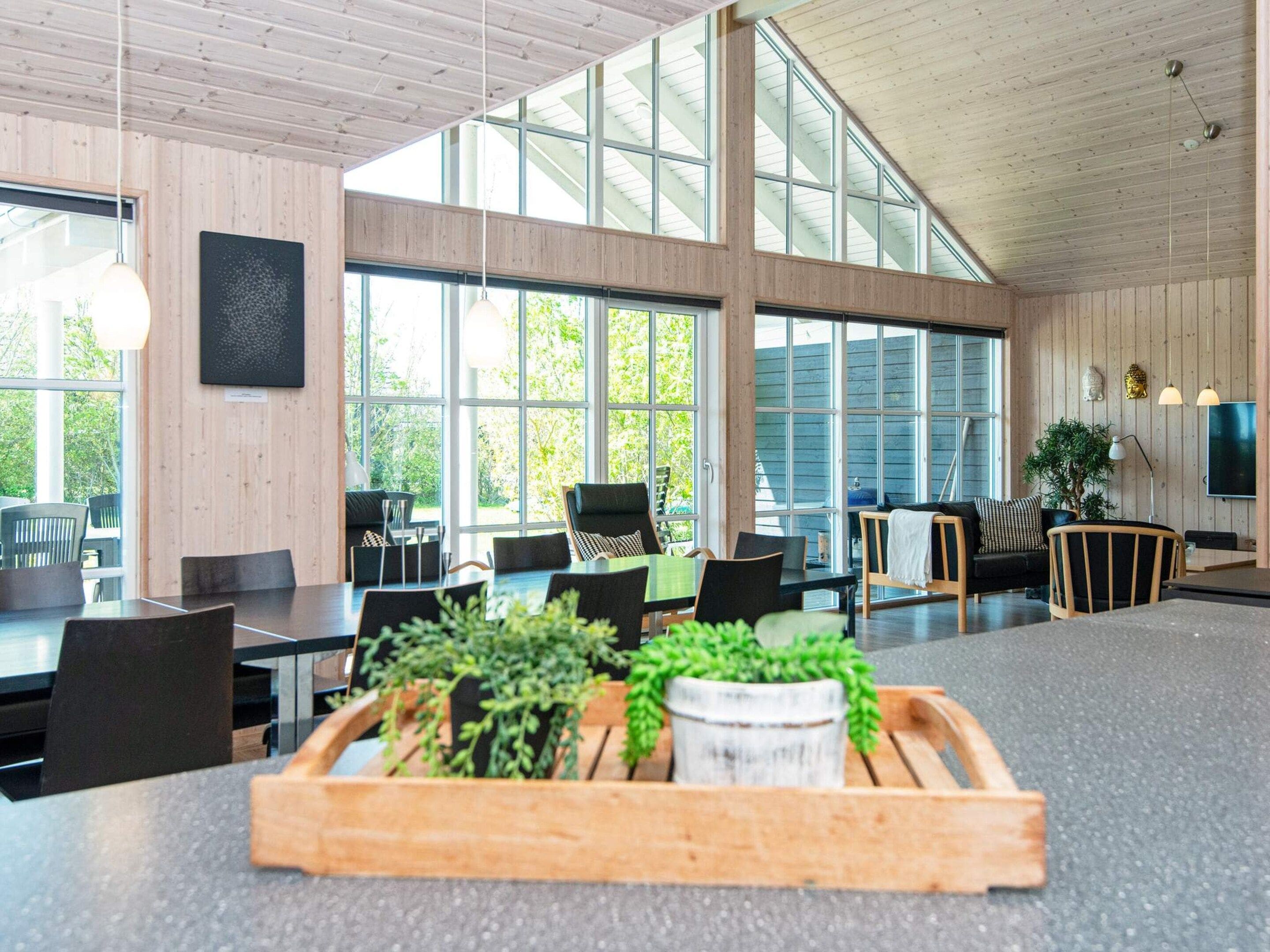 Tilava sisätila, jossa on korkeat katot, suuret ikkunat ja monipuoliset istumajärjestelyt, kuten pöytiä ja tuoleja.