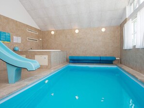 Une piscine intérieure avec un toboggan, un banc et un petit espace pour se changer.