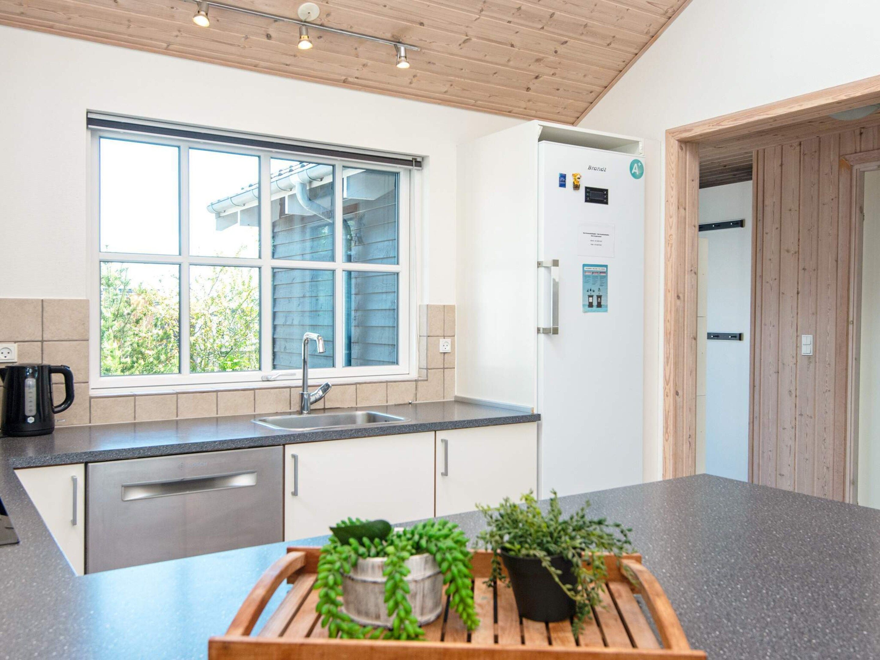 A modern kitchen with a window, stainless steel appliances, and a wooden countertop.