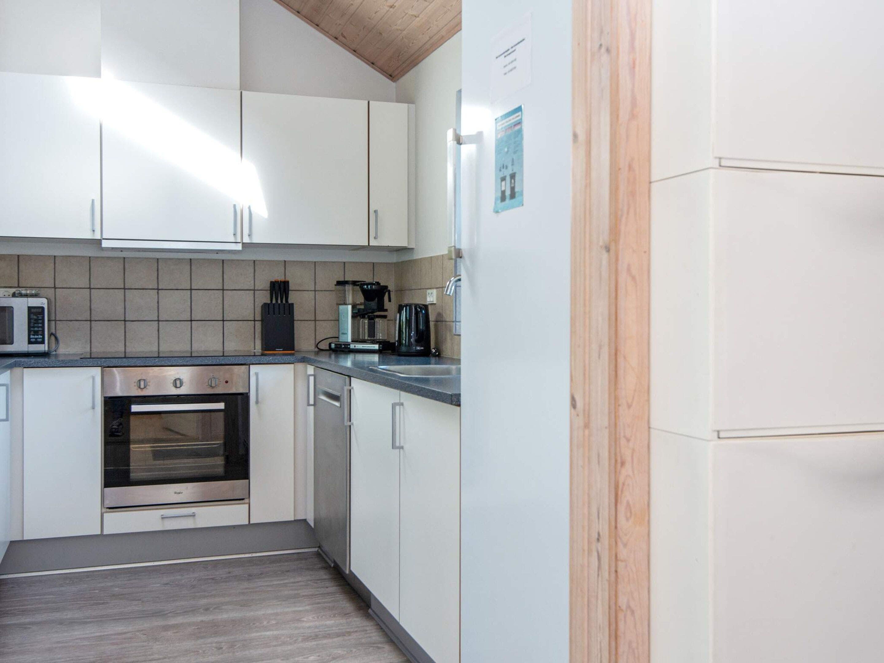 A compact kitchen with white cabinets, a built-in oven, a coffee maker, and a microwave.
