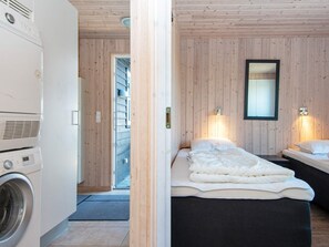 A room with a bed, a washing machine, and a wooden wall.