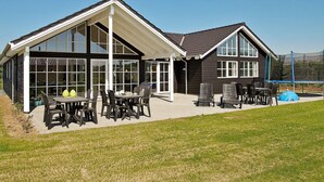 A two-story house with a covered patio area, large windows, and outdoor seating. - 5 Star Holiday Home in Odder (Odder)