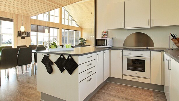 Una cocina moderna con armarios blancos, horno empotrado y microondas.
