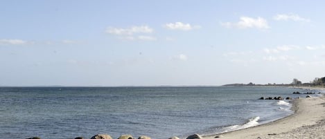 Rantaviiva, jossa on kivikkoista maastoa ja tyyni vesi.