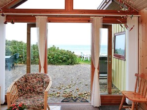 Ein Zimmer mit Meerblick, ein Holzhocker, eine Couch und eine Tür, die nach draußen führt.