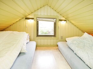 Un alojamiento pequeño y de una sola habitación con techo inclinado, ventana con vistas y dos camas.