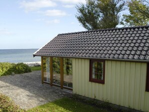 A building with a tiled roof, large glass doors, and a view of the sea. - Magical Holiday Home with Barbecue in Otterup near Sea (Otterup)