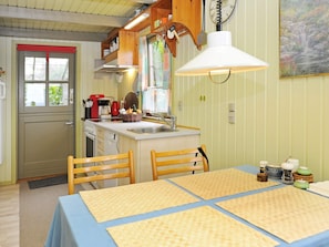 Une cuisine compacte avec un coin repas, des chaises en bois, une table avec des sets de table et un luminaire suspendu.
