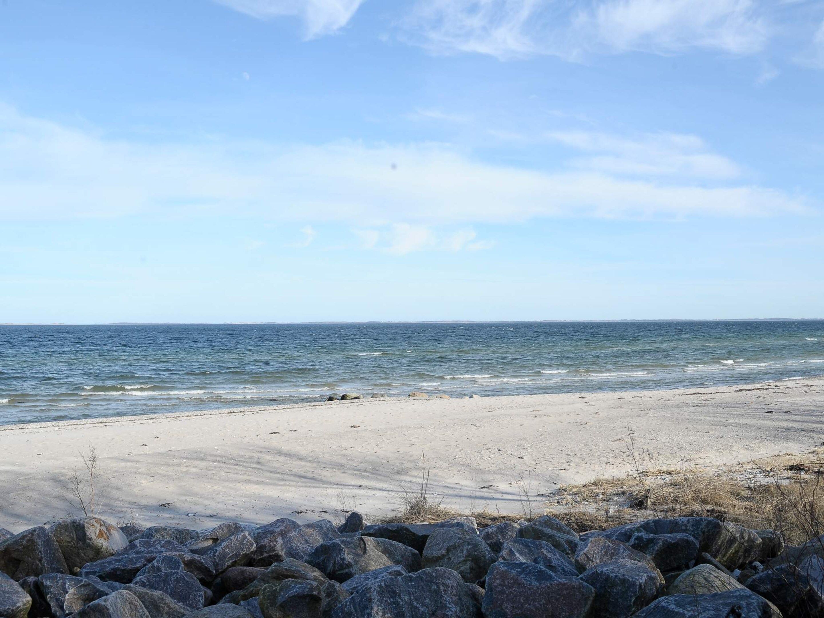 Een strand met een rotsachtige voorgrond en een helder uitzicht op de oceaan.