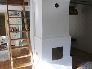 Une pièce avec une échelle en bois appuyée contre un mur blanc, un radiateur et une petite fenêtre.