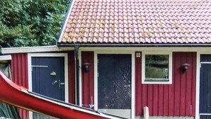 Un bâtiment rouge avec un toit en tuiles, un toboggan rouge et une brouette.