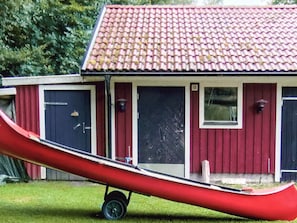 A red building with a tiled roof, a red slide, and a wheelbarrow. - 4 Person Holiday Home in Unnaryd (Unnaryd)