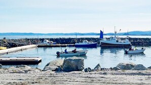 A marina with several boats docked, a pier, and a rocky shoreline. - Holiday Home in Storfosna (Orland)