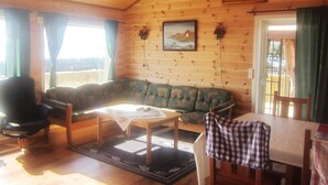 A cozy cabin interior with a wooden interior, a sofa, a dining table, and a view through a window. - Holiday Home in Storfosna (Orland)