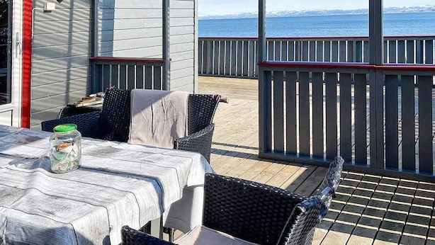 A covered outdoor seating area with a table and chairs, a view of the sea, and a wooden deck. - Holiday Home in Storfosna (Orland)