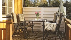 Una terrazza esterna con tavolo, sedie e un vaso di fiori.