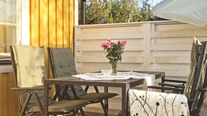 Un patio all'aperto con tavolo, sedie e un vaso di fiori.