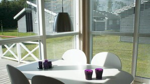 A modern outdoor dining area with a white table and chairs, surrounded by large windows with blinds. - 6 Person Holiday Home in Gudhjem-by Traum (Gudhjem)