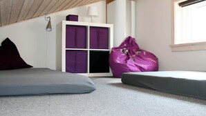 A cozy room with a sloped ceiling, a white storage unit with purple cushions, a purple bean bag, and a grey sofa. - 6 Person Holiday Home in Gudhjem-by Traum (Gudhjem)