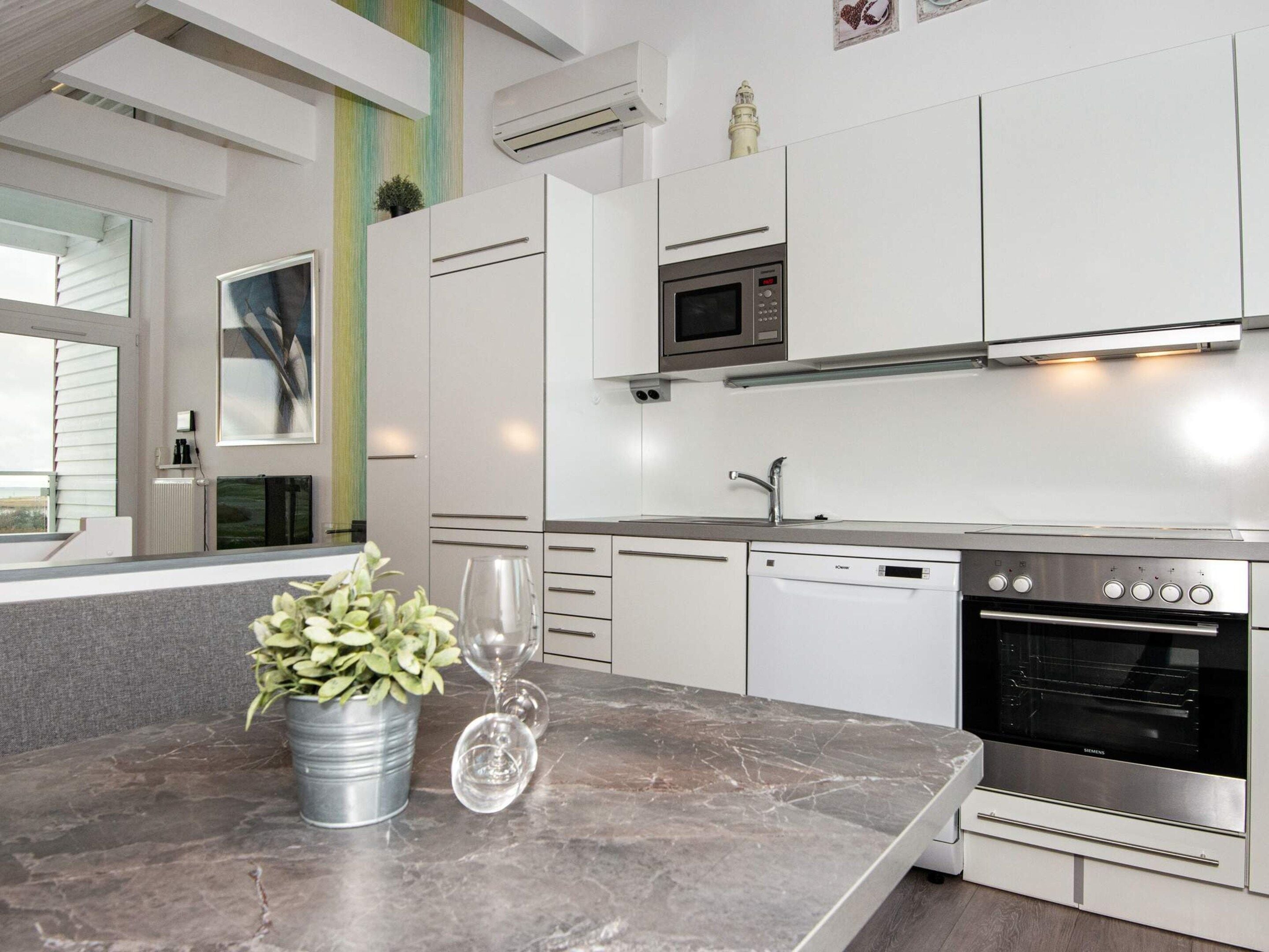 Een moderne keuken met witte kastjes, een inbouwoven en een vaatwasser.