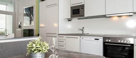 A modern kitchen with white cabinets, a built-in oven, and a dishwasher.