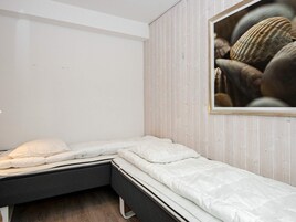 Un dormitorio con una cama, una mesita de noche pequeña y un cuadro colgado en la pared.