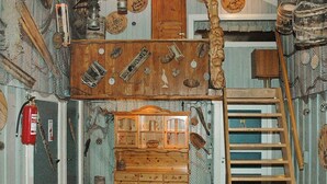 A rustic room with a wooden bench, a ladder, a wooden cabinet, and various tools and objects on the walls. - 6 Person Holiday Home in Oksvoll (Orland)