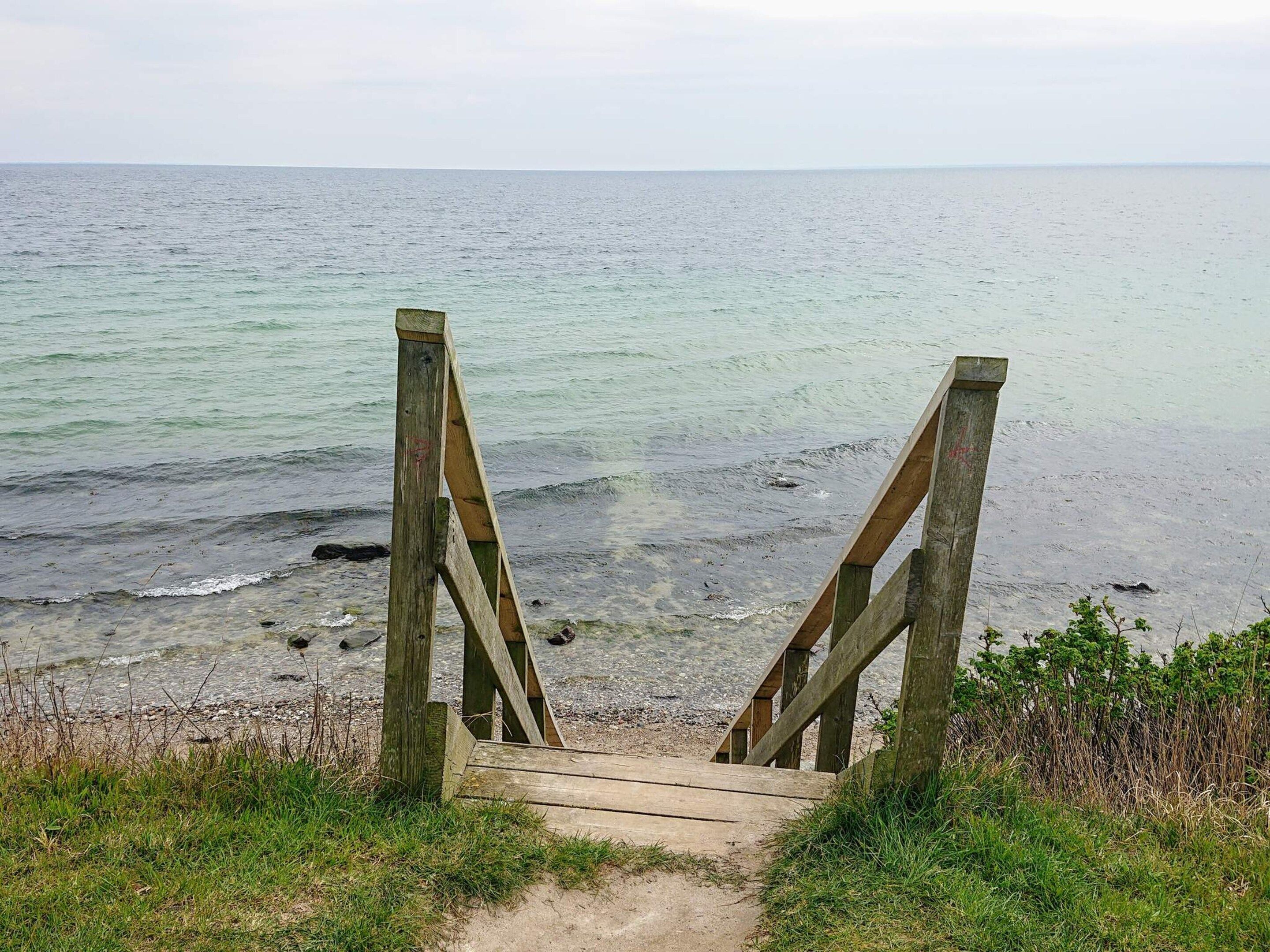 A wooden staircase leading to a beach with a view of the sea.