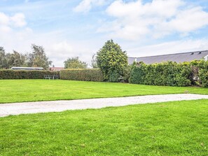 A well-maintained grassy area with a paved path, surrounded by neatly trimmed hedges and trees. - 5 Star Holiday Home in Haderslev (Haderslev)